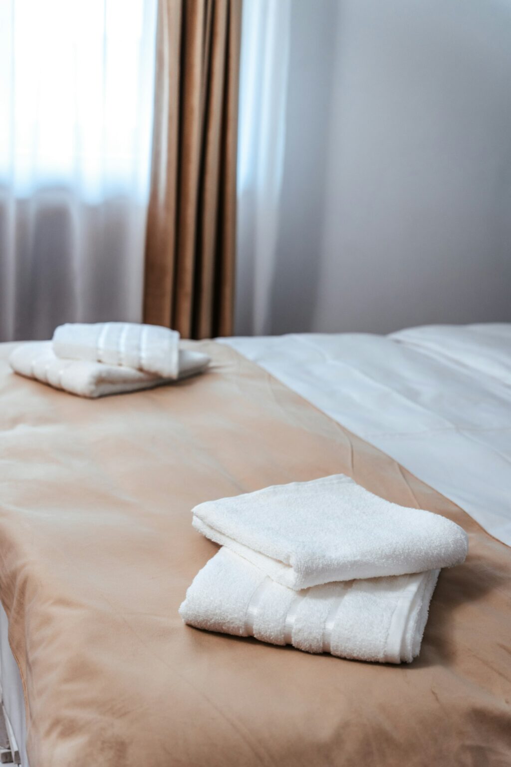 Folded white towels on a freshly made hotel bed